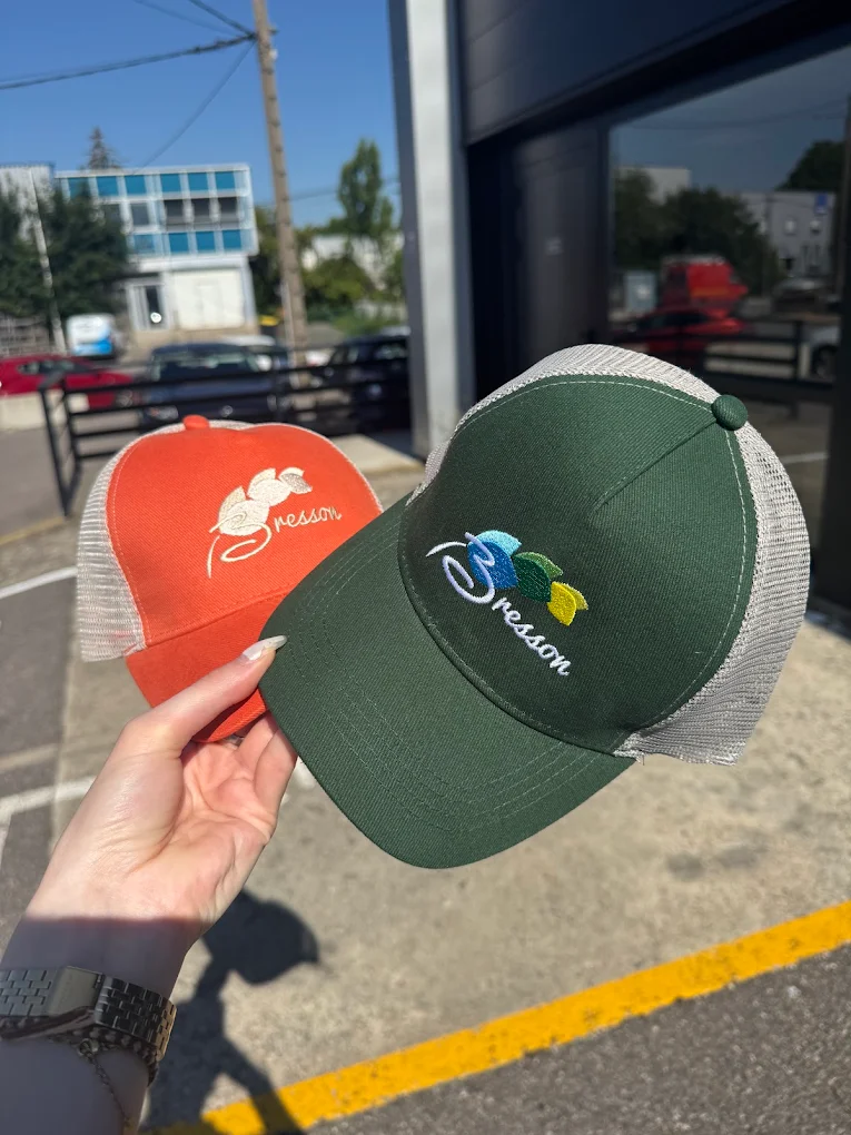 Deux casquettes brodées d'un logo client, l'une verte, l'autre orange